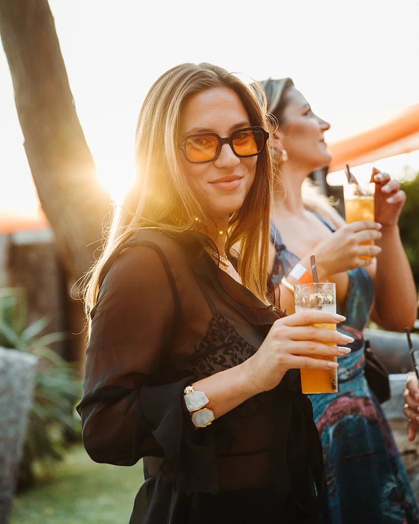 A woman enjoying a cocktail made with Laval Pelinkovac at a summer event.